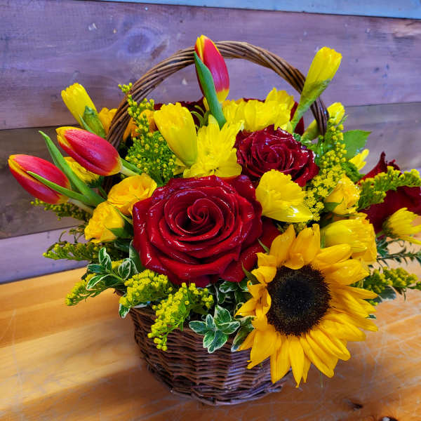 Basket arrangement with red roses, yellow tulips, and a sunflower