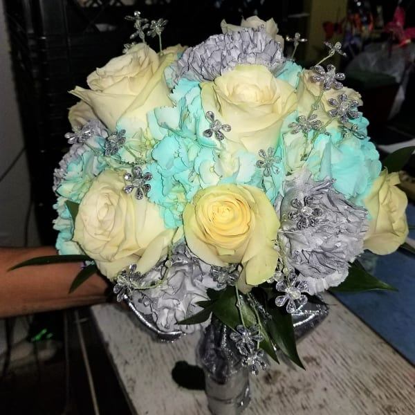 Bouquet of cream roses, blue carnations, and silver floral accents