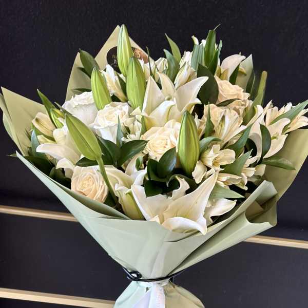White lily and rose bouquet wrapped in pale green paper