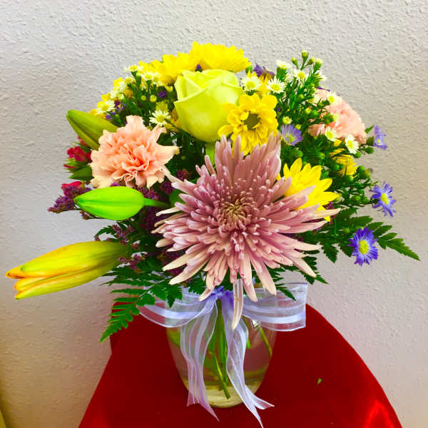 Mixed bouquet in a glass vase with pink, yellow, and purple flowers
