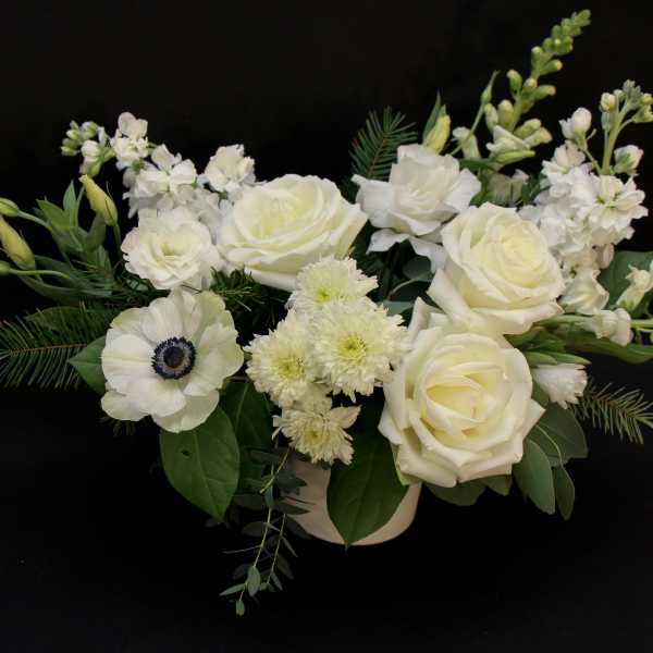 White floral arrangement with roses and anemone in a low vase