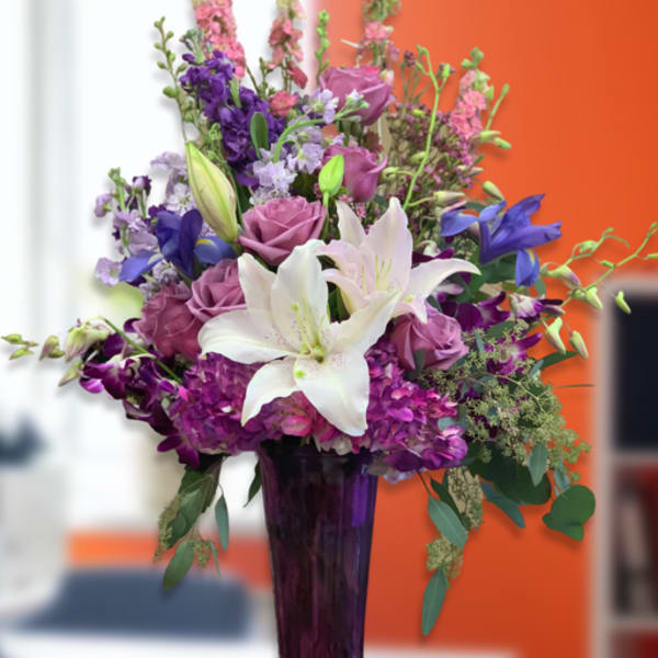 Purple and white floral arrangement in a tall vase