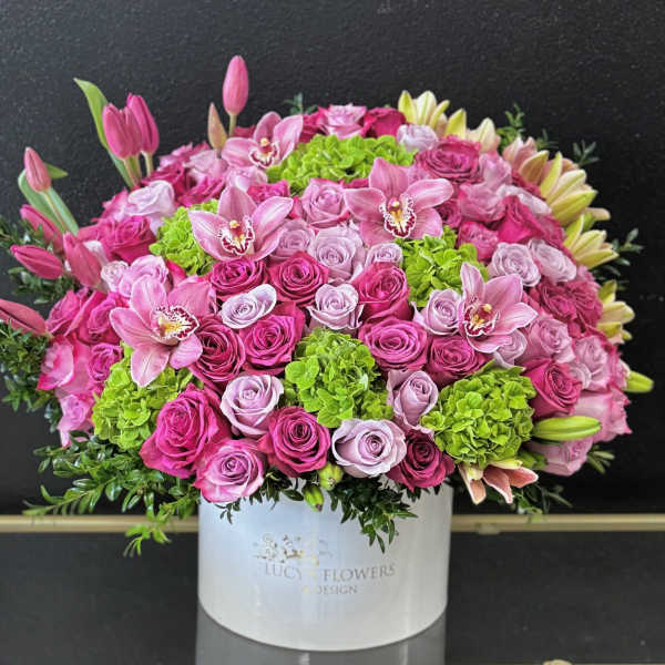 Large pink and lavender flower arrangement in a white box