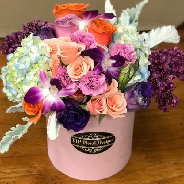 Mixed bouquet of roses, orchids, and hydrangeas in a pink hat box