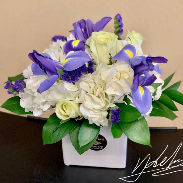 Bouquet of white roses, hydrangeas, and purple irises in a white vase