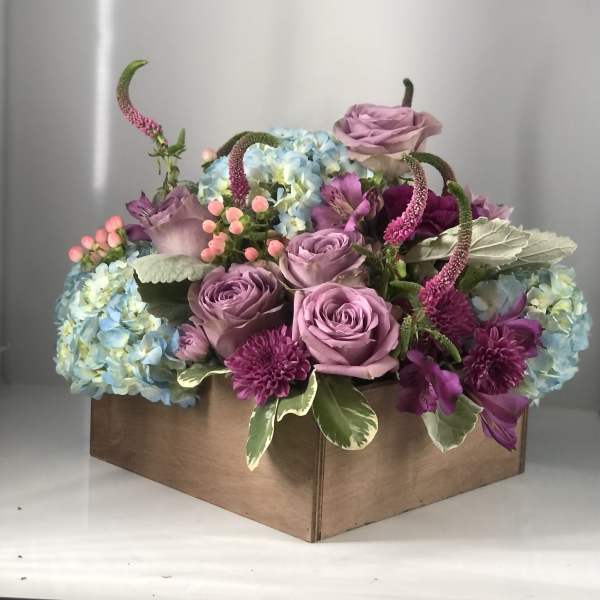 Lavender roses and blue hydrangeas in a cardboard box