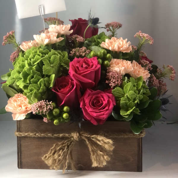 Mixed bouquet in a wooden box with pink roses and green hydrangeas