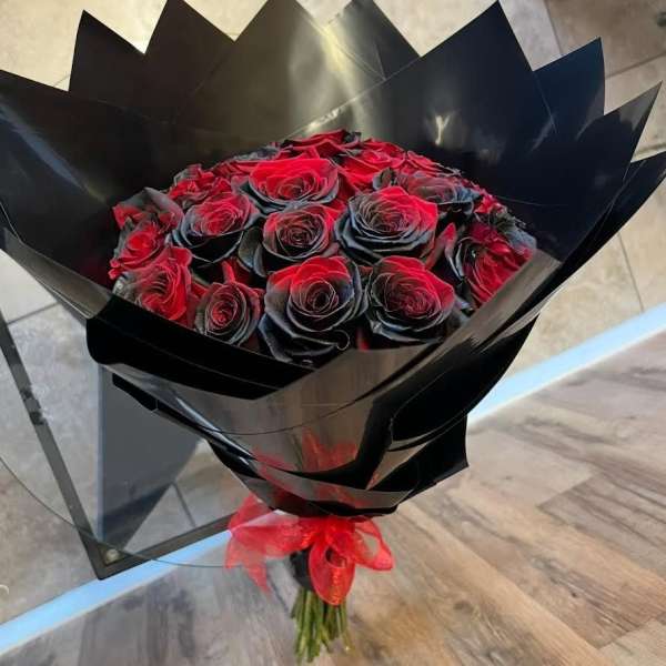 Bouquet of red roses wrapped in black paper with a red ribbon