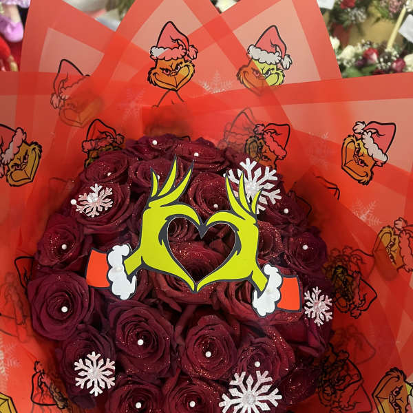Bouquet of dark red roses wrapped in bright red Grinch-themed paper