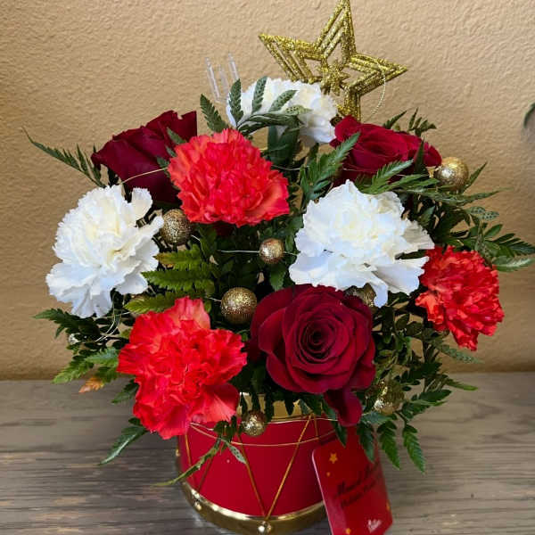 Red roses and white and red carnations in a red gift container with gold accents