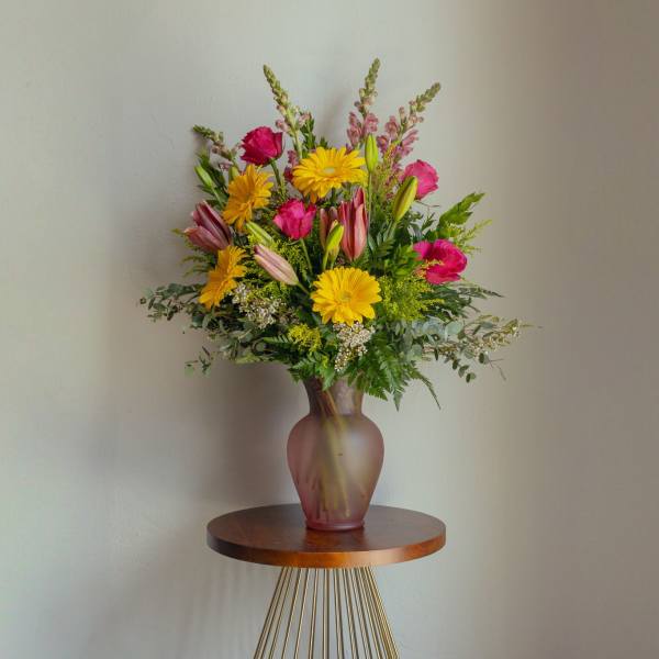 Mixed bouquet of yellow daisies, pink lilies, and magenta blooms in a vase