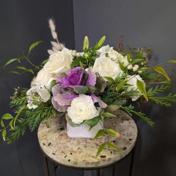 White and purple floral arrangement in a white vase