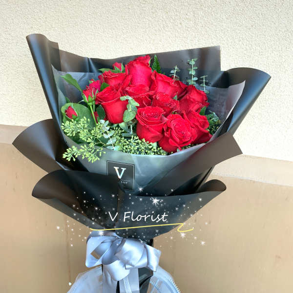 Bouquet of red roses wrapped in black paper with a silver ribbon