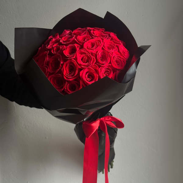 Bouquet of red roses wrapped in black paper with a red ribbon