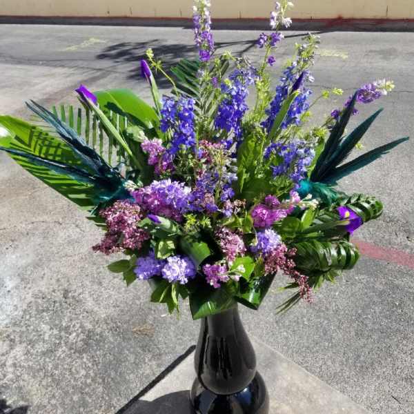 Tall purple and blue floral arrangement in a black vase
