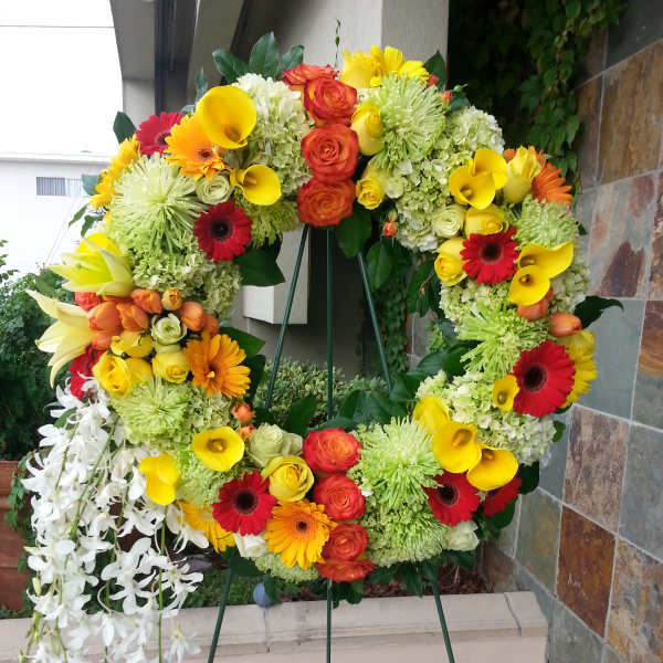 Large floral wreath on an easel with yellow, orange, red, and white blooms
