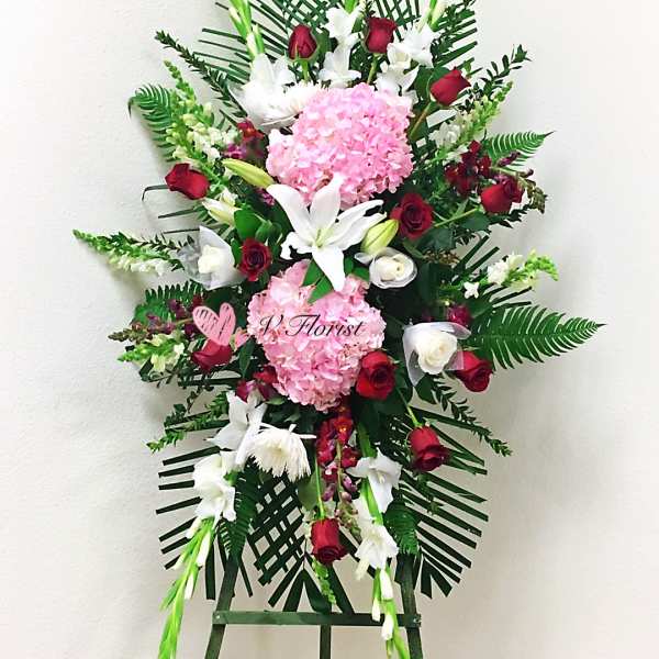 Standing floral spray with pink hydrangeas, red roses, and white lilies