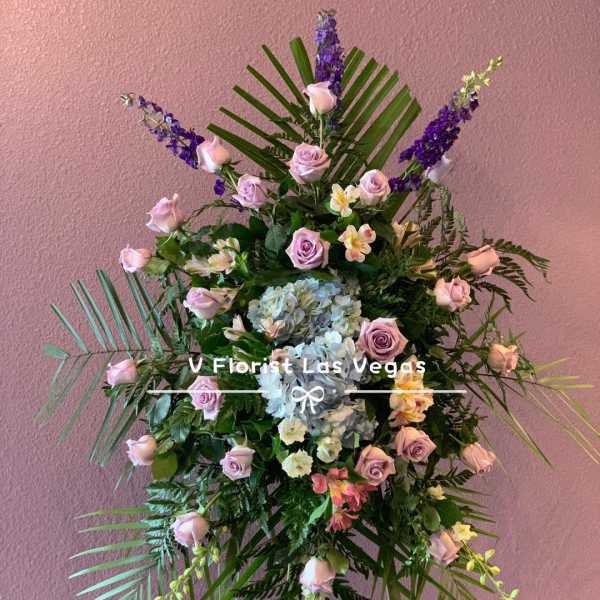 Standing floral spray with pink roses, blue hydrangea, and purple accents