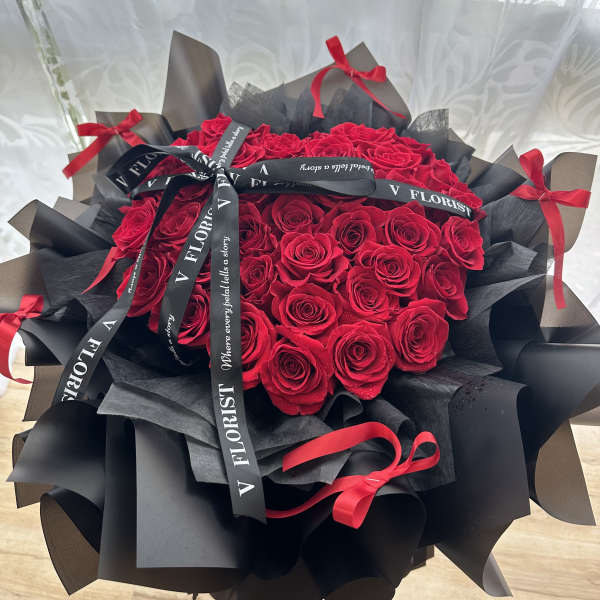 Bouquet of red roses wrapped in black paper with red ribbons