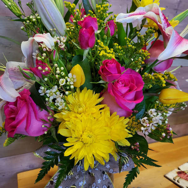 Bouquet of pink roses, yellow chrysanthemums, and white lilies in a vase