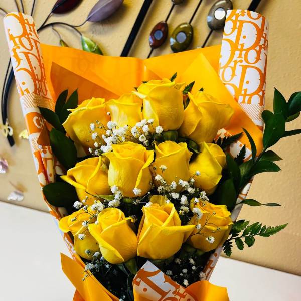 Bouquet of yellow roses with white filler flowers in orange wrapping