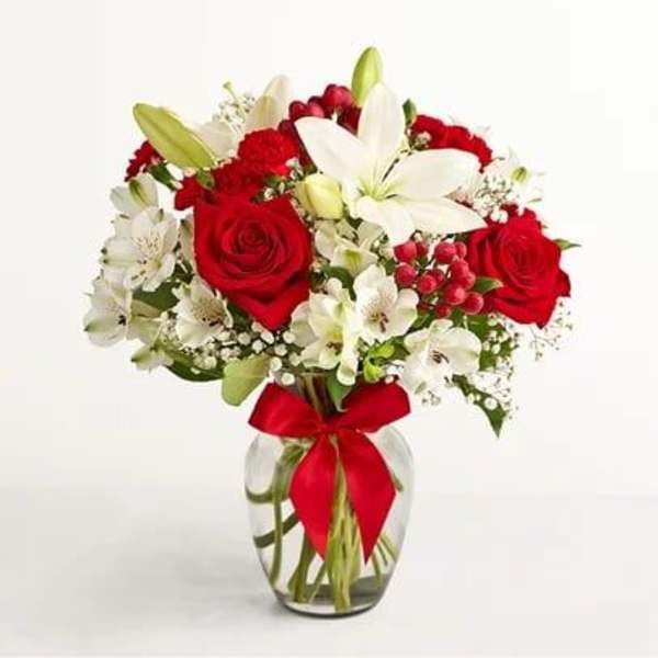 Red roses and white lilies in a glass vase with a red ribbon