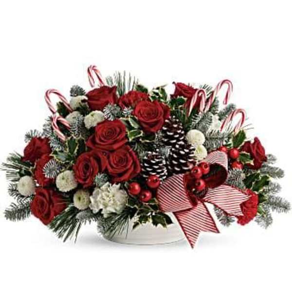 Red roses and white flowers in a low holiday centerpiece with candy canes and pinecones