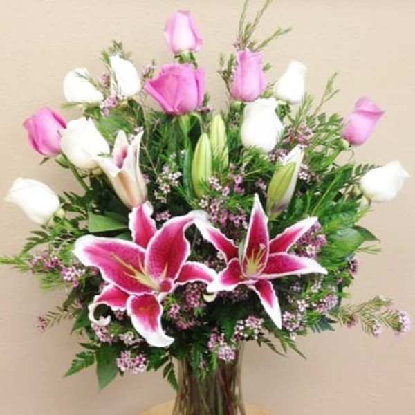 Pink and white lilies with roses in a glass vase