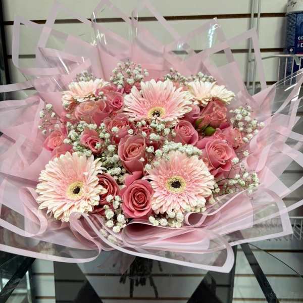 Pink bouquet with roses, gerbera daisies, and baby's breath wrapped in pink paper