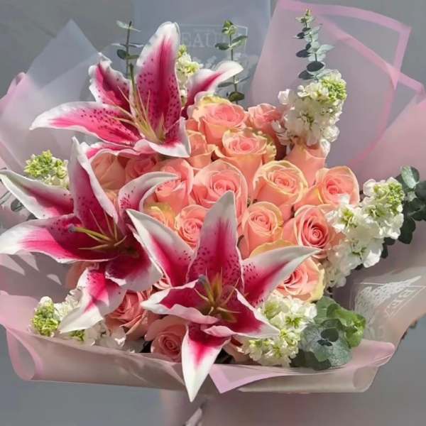Bouquet of pink roses and pink lilies wrapped in pale pink paper