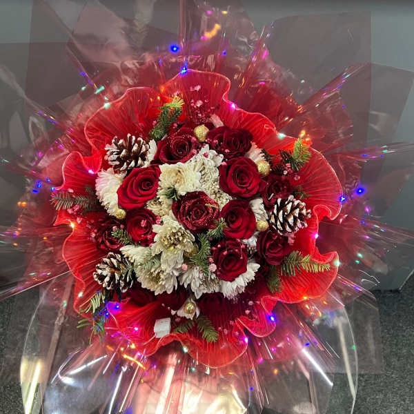 Red and white rose bouquet with pinecones and lights in clear wrap