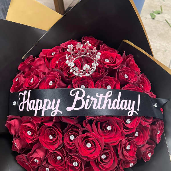 Bouquet of red roses with a "Happy Birthday" ribbon and jeweled crown