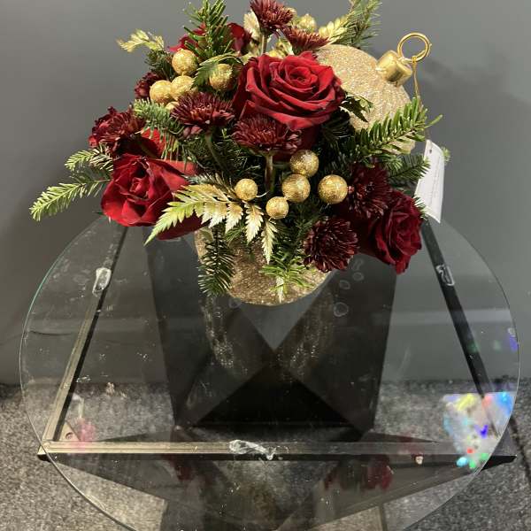 Red roses in a gold ornament-shaped container with pine and gold accents