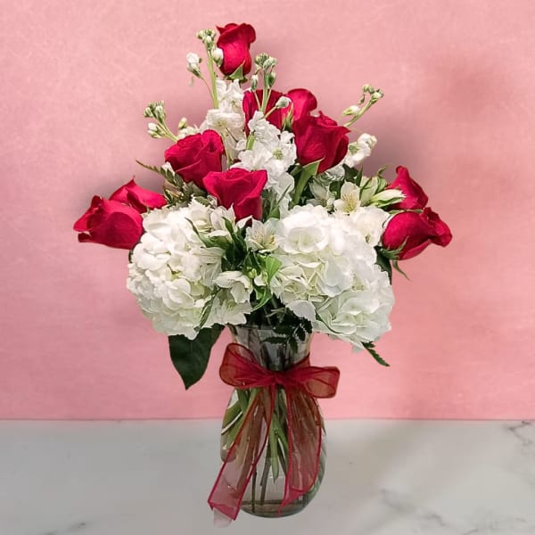 Bouquet of red roses and white hydrangeas in a glass vase with a red ribbon