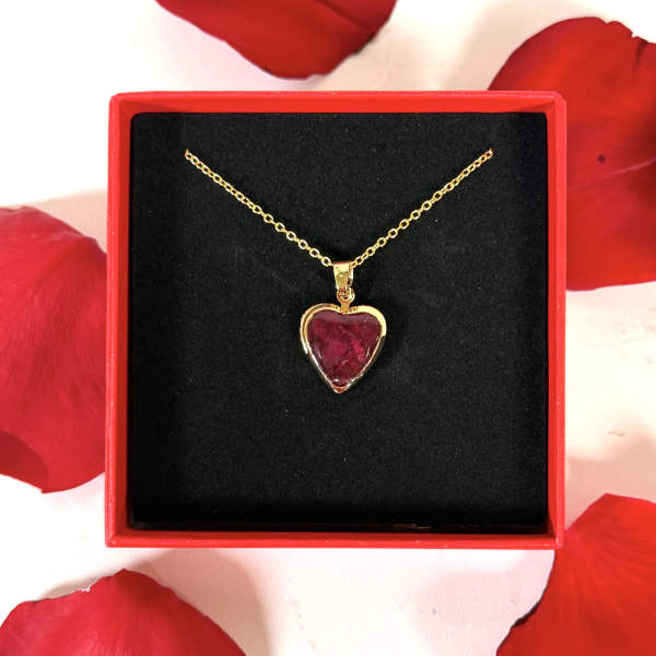 Gold heart pendant necklace in a red gift box with rose petals