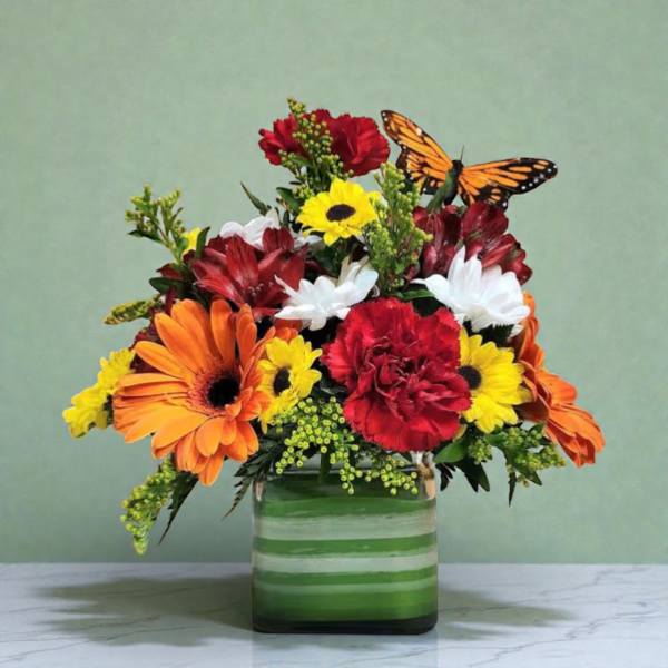 Mixed bouquet of orange, red, yellow, and white flowers in a green striped vase