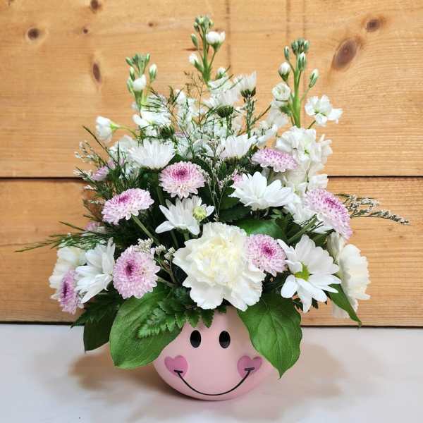 Pink smiley-face pot holding white and pale pink flowers