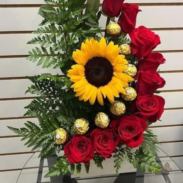 Red roses and a sunflower arranged with gold chocolates in a vase