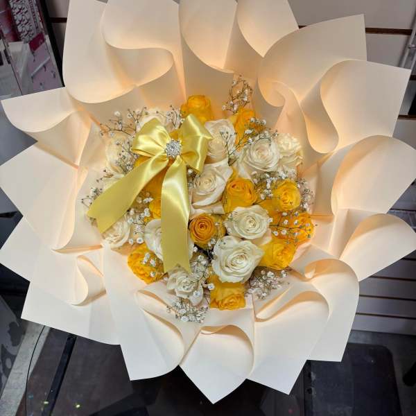 Bouquet of yellow and white roses with a satin bow in cream wrap