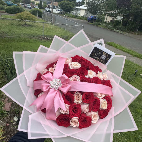 Large bouquet of red and blush roses wrapped in pink paper with a ribbon