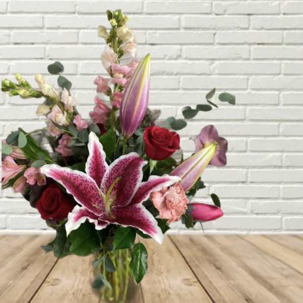 Bouquet of pink lilies and red roses in a glass vase