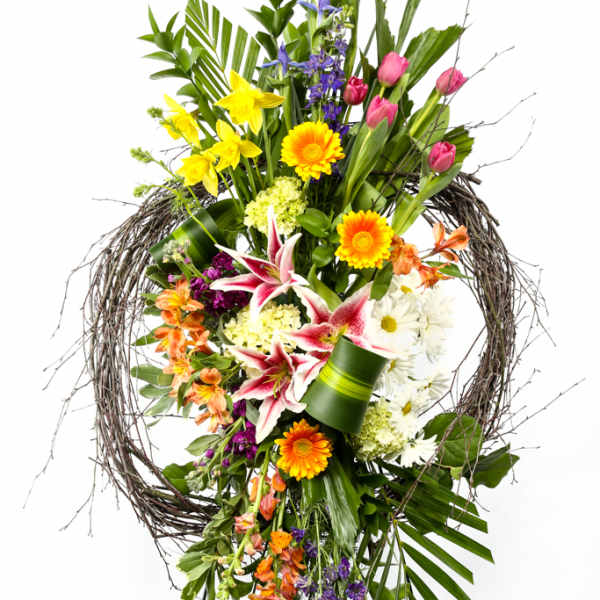 Tall floral standing spray with mixed blooms in a twig wreath frame