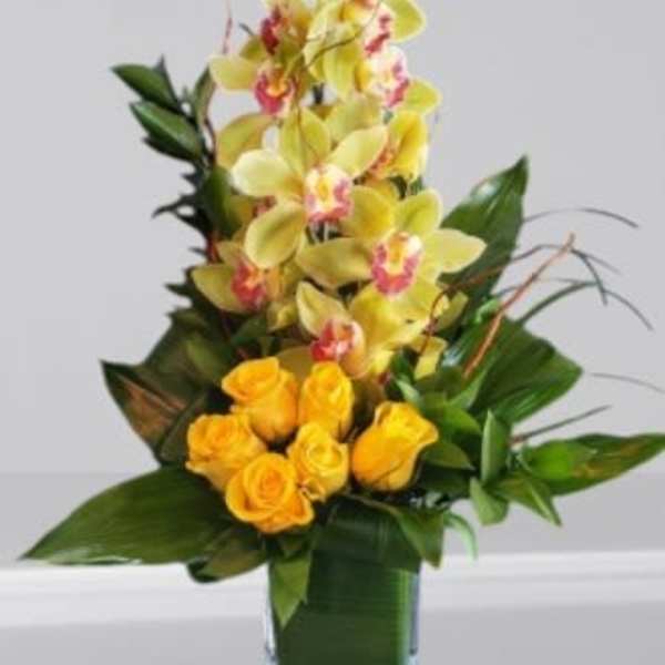 Yellow orchids and roses in a square glass vase