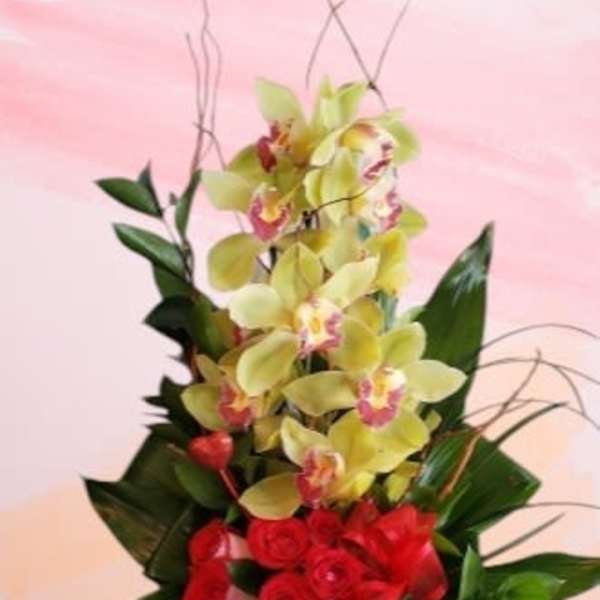 Red roses and yellow orchids in a glass vase