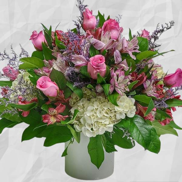 Pink roses and mixed blooms in a white vase