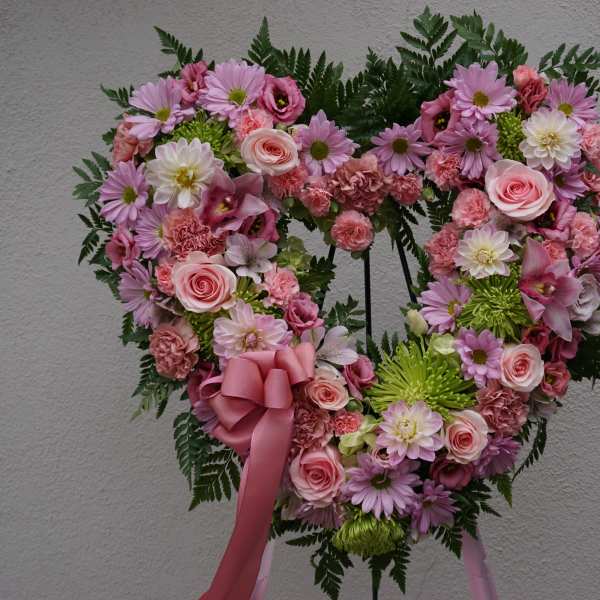 Heart-shaped floral wreath with pink and white flowers and a pink ribbon