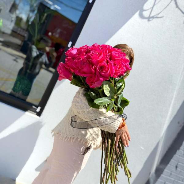 Large bouquet of hot pink roses held by a person outdoors