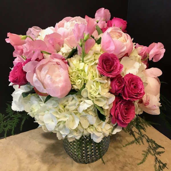 Pink and white flower arrangement in a textured glass vase
