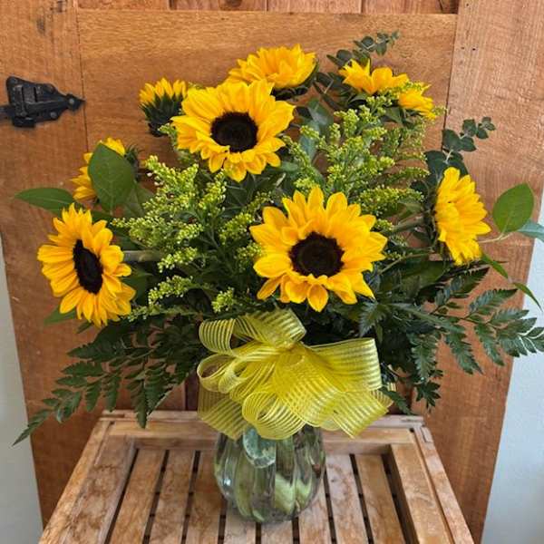 Sunflower bouquet in a glass vase with a yellow ribbon