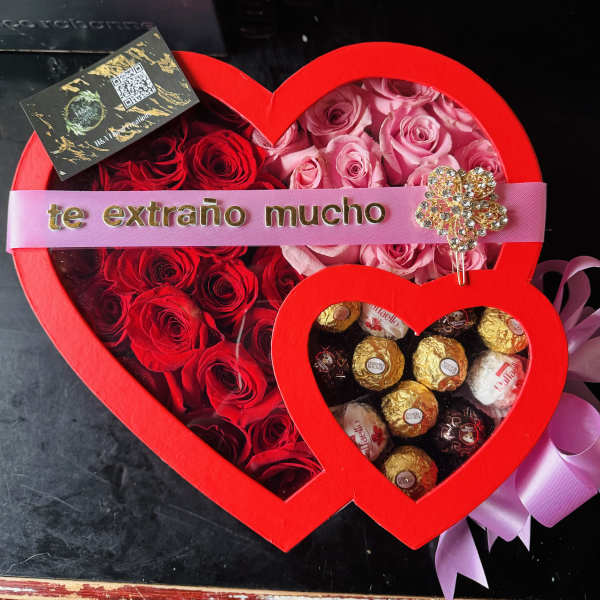 Heart-shaped box of red and pink roses with chocolates and a ribbon